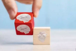 Mão posicionando blocos com ícones de cérebro e coração, simbolizando o equilíbrio entre razão e emoção — essência da inteligência emocional.