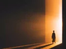 Pessoa caminhando da escuridão para uma luz dourada, simbolizando o despertar da consciência e o caminho do autoconhecimento.