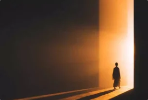 Pessoa caminhando da escuridão para uma luz dourada, simbolizando o despertar da consciência e o caminho do autoconhecimento.