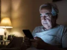 Idoso usando celular à noite, representando o uso excessivo de telas em idosos e seus impactos no sono e na saúde mental.