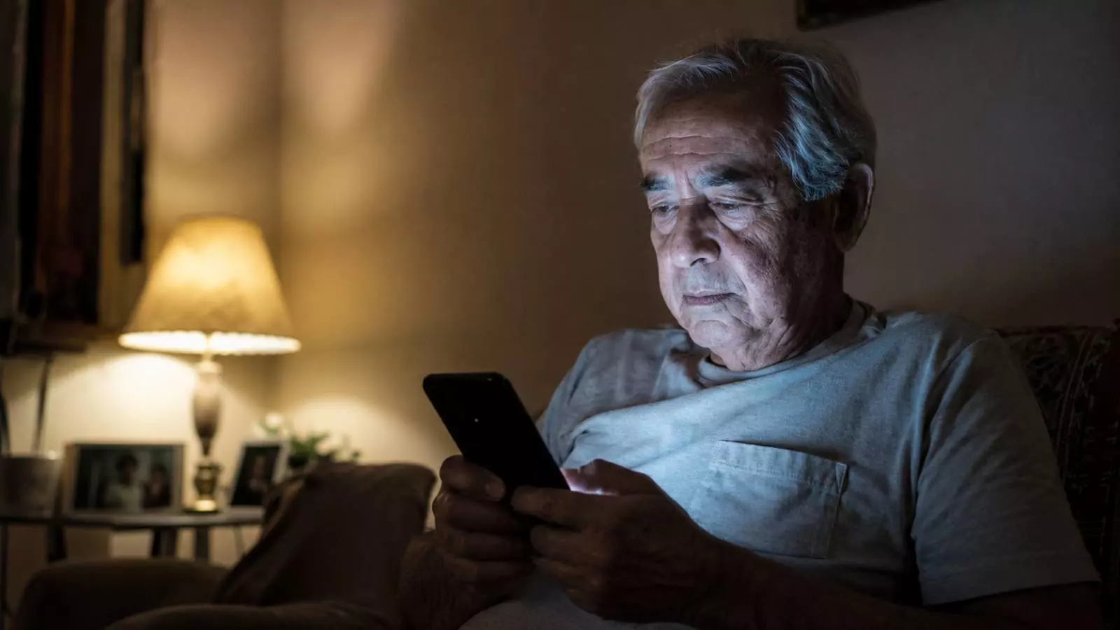 Idoso usando celular à noite, representando o uso excessivo de telas em idosos e seus impactos no sono e na saúde mental.
